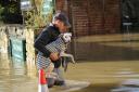 A walker carries his dog through the Bradford on Avon floods.