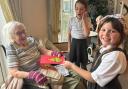 Two of the Keevil Primary School pupils give a Christmas card to one of the Blenheim House care home residents.