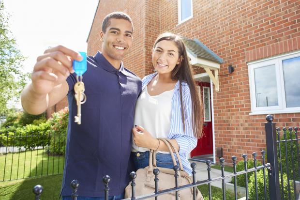 Couple smiling outside new build property. Photo: Getty images.