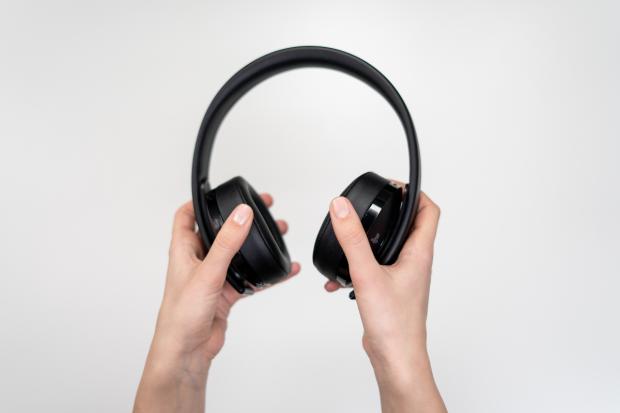 A person holding up headphones. Credit: Canva