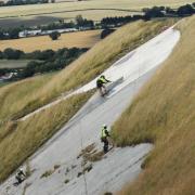James Preston grinding away a few millimetres of the surface with Richard Sharp and Tim Dixon cleaning weeds from the cracks  during  the cleaning up of the Westbury White Horse.