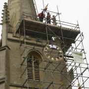 The Christ Church clock face is hauled back up to the church spire to be fixed in place.