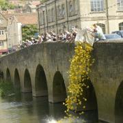 Town wardens tip the bag full of yellow ducks over the town bridge to start the race.